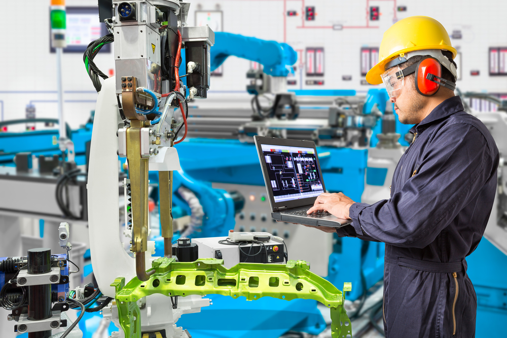Engineer working on a laptop in an automated manufacturing facility